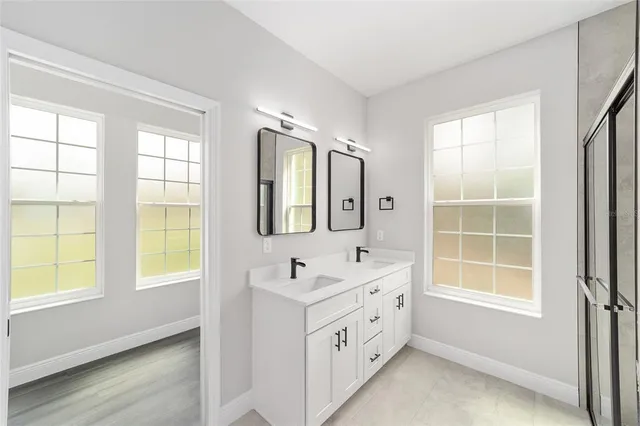 a bathroom with double vanity and a window