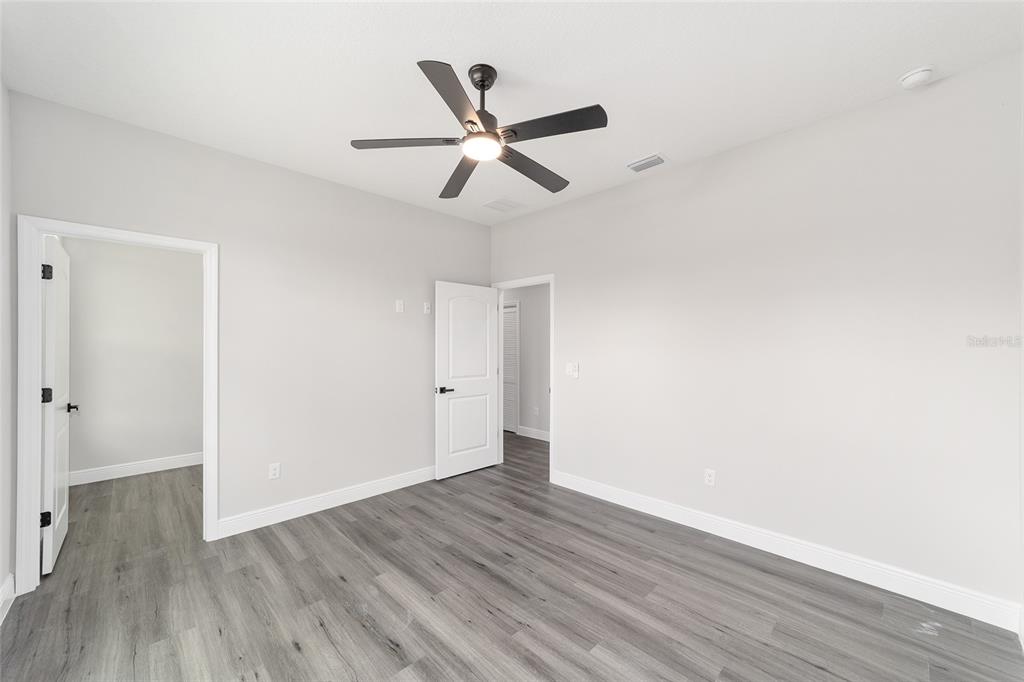 1370 Northeast 151 Avenue Williston, FL 32696 - Photo 28 of 51 a view of an empty room with wooden floor and a ceiling fan