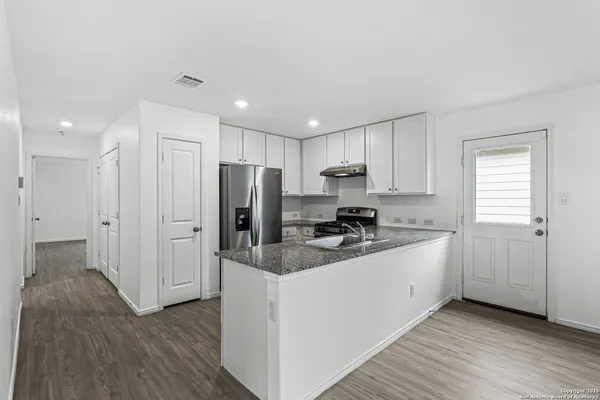a kitchen with stainless steel appliances granite countertop a refrigerator a sink and a stove