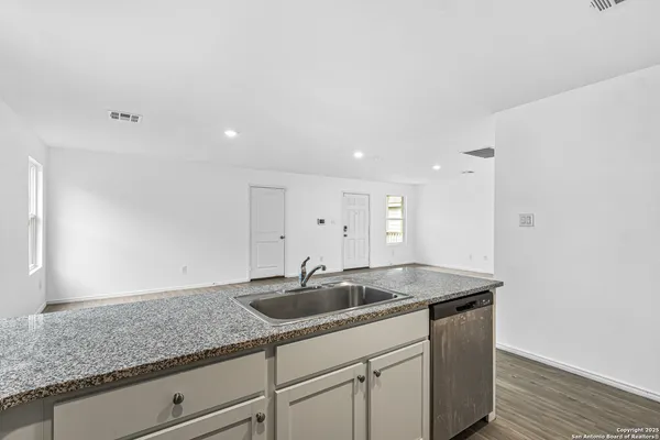 a kitchen with granite countertop white cabinets and sink