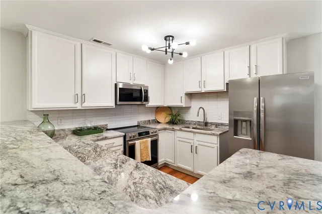 a kitchen with stainless steel appliances granite countertop a refrigerator stove microwave and sink