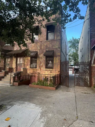 a view of a brick house with many windows next to a yard