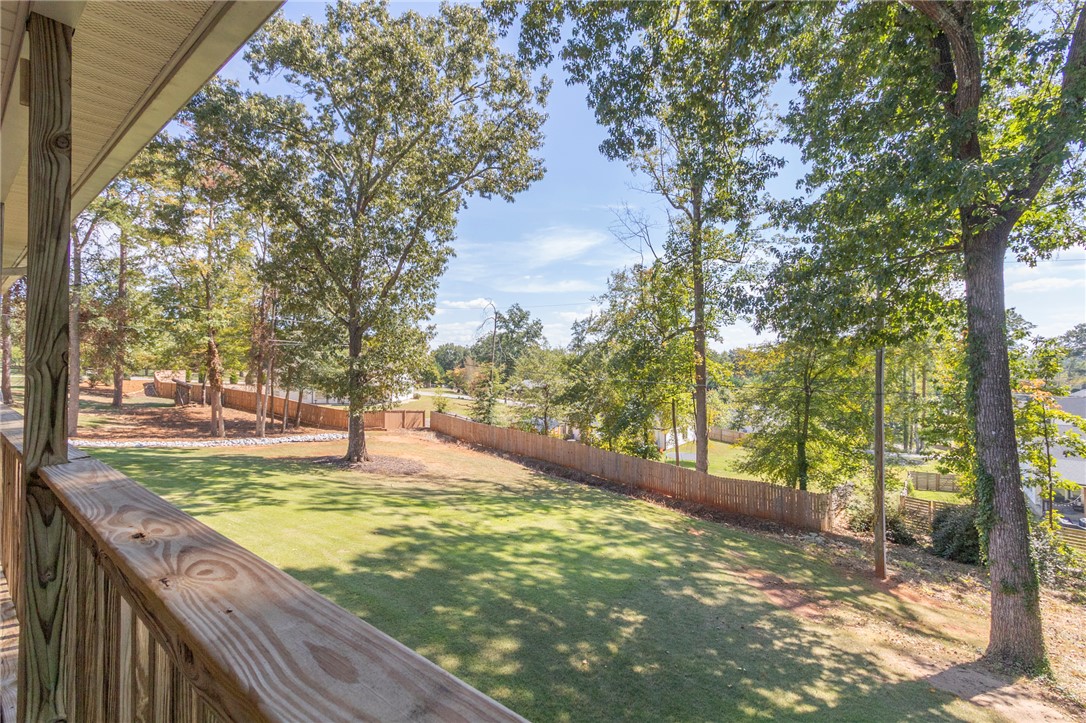 608 Robin Hood Lane Anderson, SC 29621 - Photo 24 of 36 Mature trees frame a sweeping lawn enclosed by privacy fencing, viewed from the wooden deck.