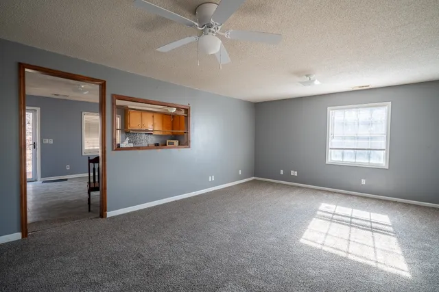 an empty room with windows and fan