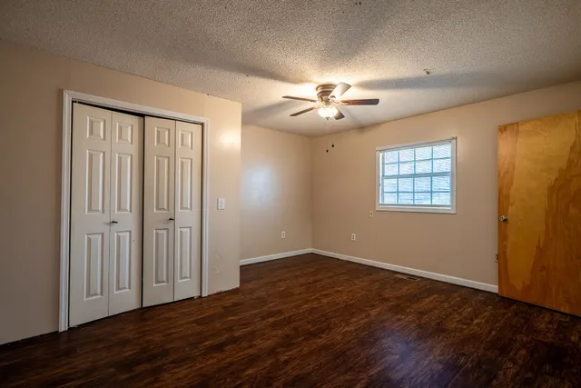 a view of an empty room with a window and wooden floor