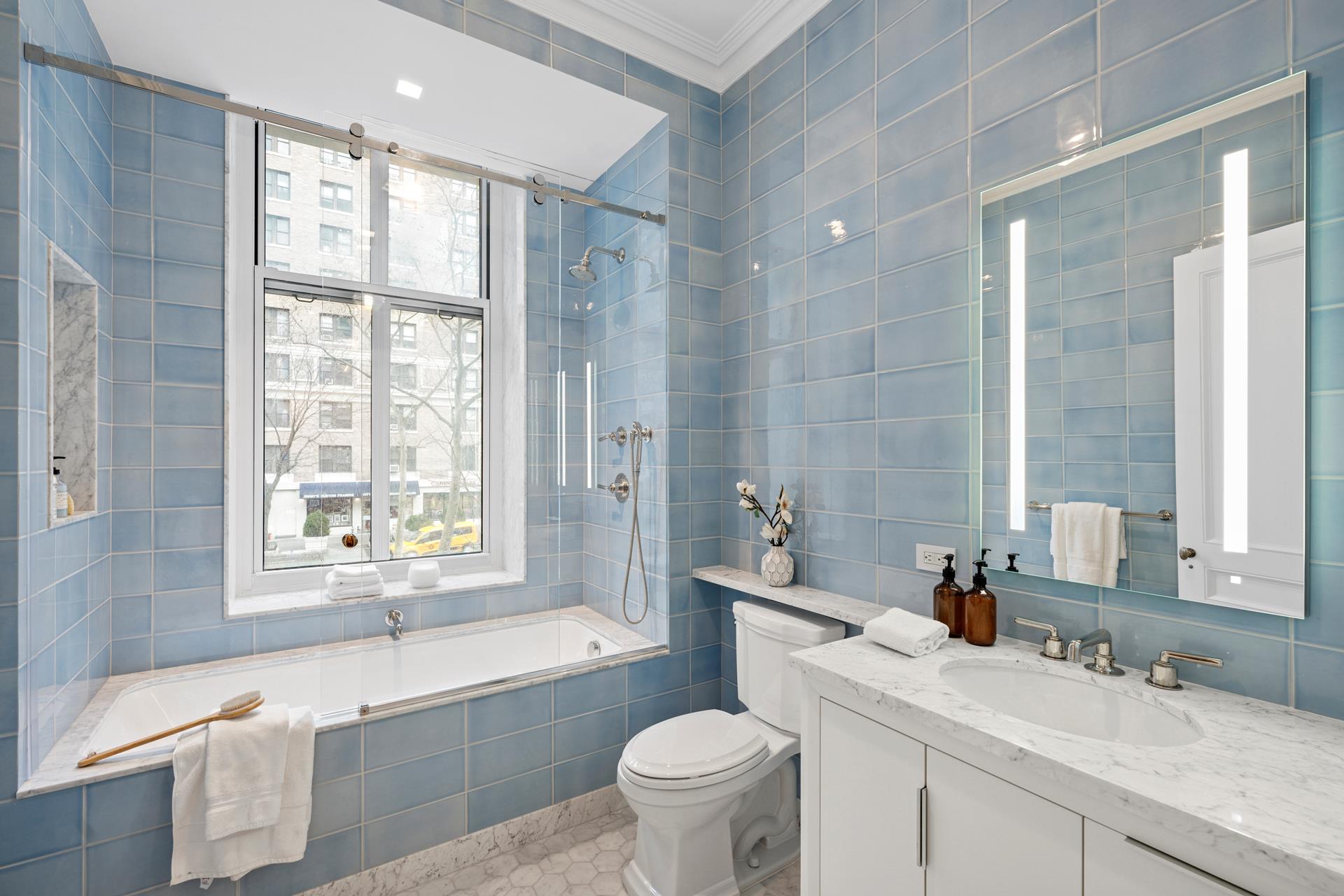 390 West End Avenue, Unit 2A Manhattan, NY 10024 - Photo 11 of 27 a bathroom with a granite countertop sink a large mirror a bathtub and window