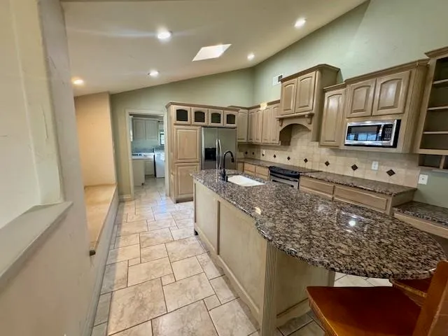 a large kitchen with stainless steel appliances granite countertop a stove and a sink