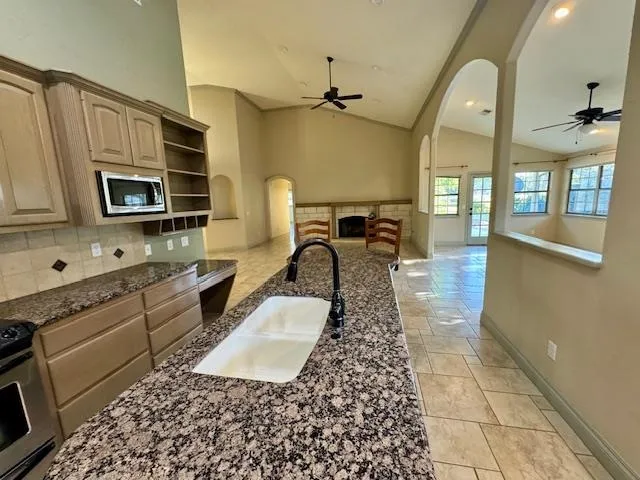 a kitchen with granite countertop a stove a sink and a microwave