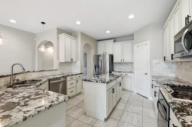 a kitchen with stainless steel appliances granite countertop a stove a sink a refrigerator and cabinets