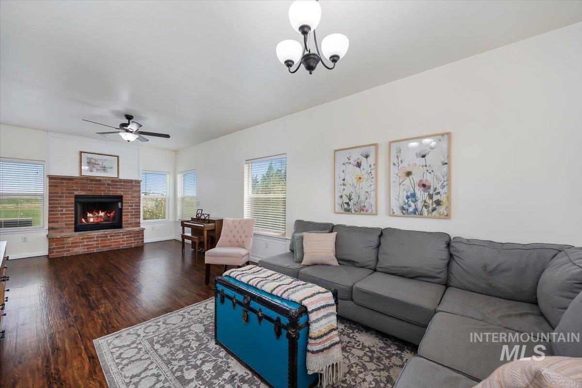 3813 North 2456 East Filer, ID 83328 - Photo 12 of 50 Living room with dark wood finished floors, a ceiling fan, and a fireplace