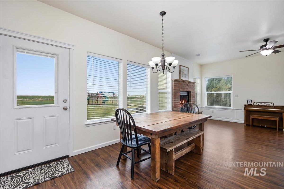 3813 North 2456 East Filer, ID 83328 - Photo 16 of 50 Dining space with ceiling fan, dark wood-style floors, a chandelier, and a fireplace