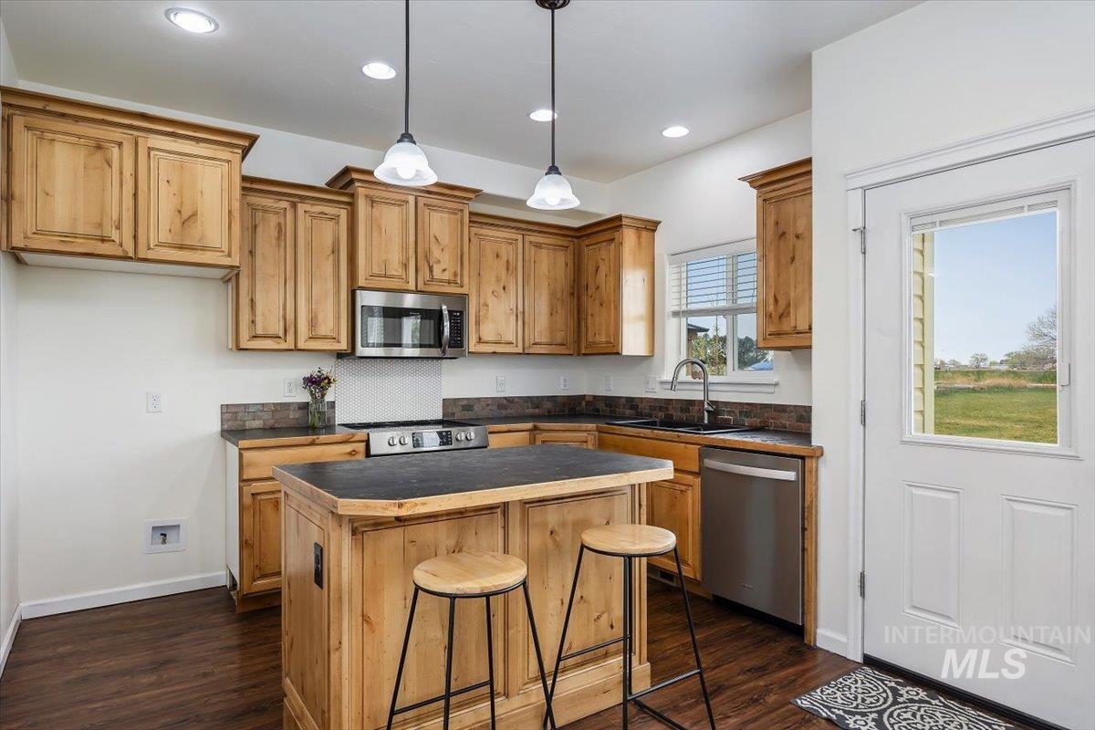 3813 North 2456 East Filer, ID 83328 - Photo 18 of 50 Kitchen featuring dark countertops, a center island, stainless steel appliances, a kitchen bar, and decorative light fixtures
