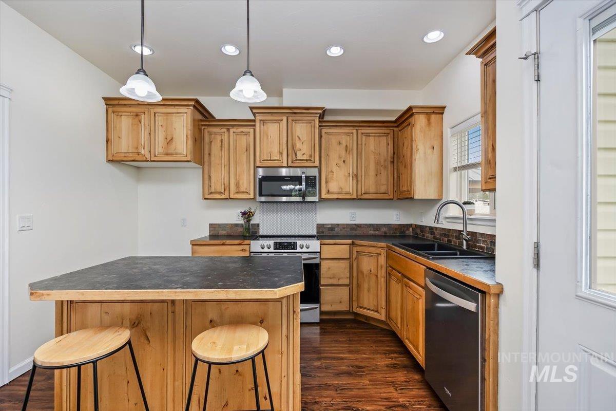 3813 North 2456 East Filer, ID 83328 - Photo 20 of 50 Kitchen with stainless steel appliances, dark countertops, a breakfast bar area, a center island, and dark wood-type flooring