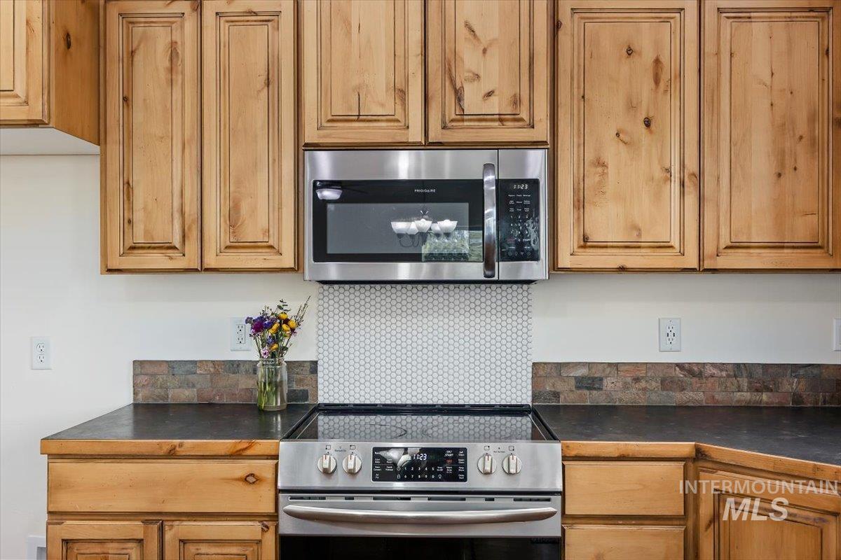 3813 North 2456 East Filer, ID 83328 - Photo 21 of 50 Kitchen with dark countertops, stainless steel appliances, backsplash, and wood finish cabinetry