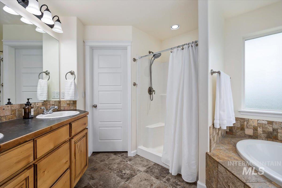 3813 North 2456 East Filer, ID 83328 - Photo 30 of 50 Full bathroom with a garden tub, a stall shower, double vanity, and stone finish floors