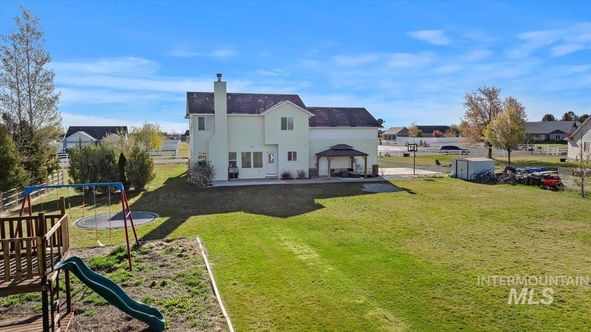 3813 North 2456 East Filer, ID 83328 - Photo 39 of 50 Back of property featuring a patio area, a residential view, a chimney, a playground, and a storage shed