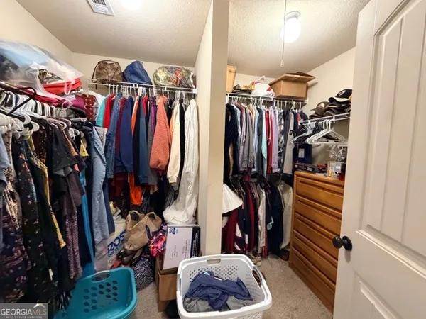 a view of walk in closet with clothes