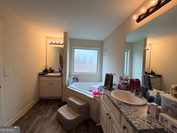 a bathroom with a granite countertop sink a mirror and a bathtub