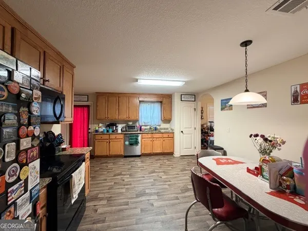 a kitchen with stainless steel appliances granite countertop a stove a refrigerator a sink dishwasher with a dining table and chairs with wooden floor