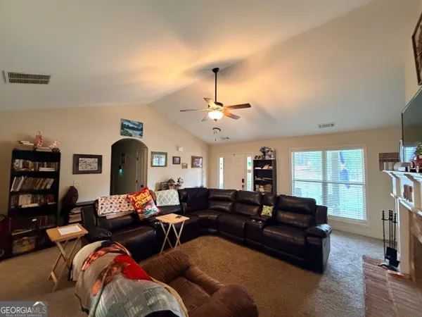 a living room with furniture a ceiling fan and a window