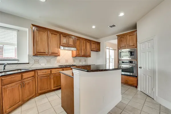 a kitchen with stainless steel appliances granite countertop a refrigerator and wooden cabinets
