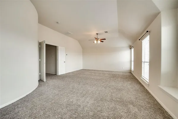an empty room with chandelier fan and windows