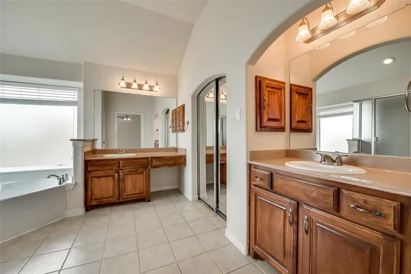 a large bathroom with a granite countertop double vanity sink a mirror and a bathtub