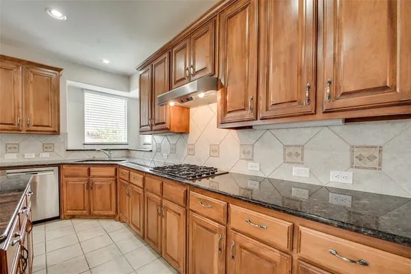 a kitchen with stainless steel appliances granite countertop a sink stove and cabinets
