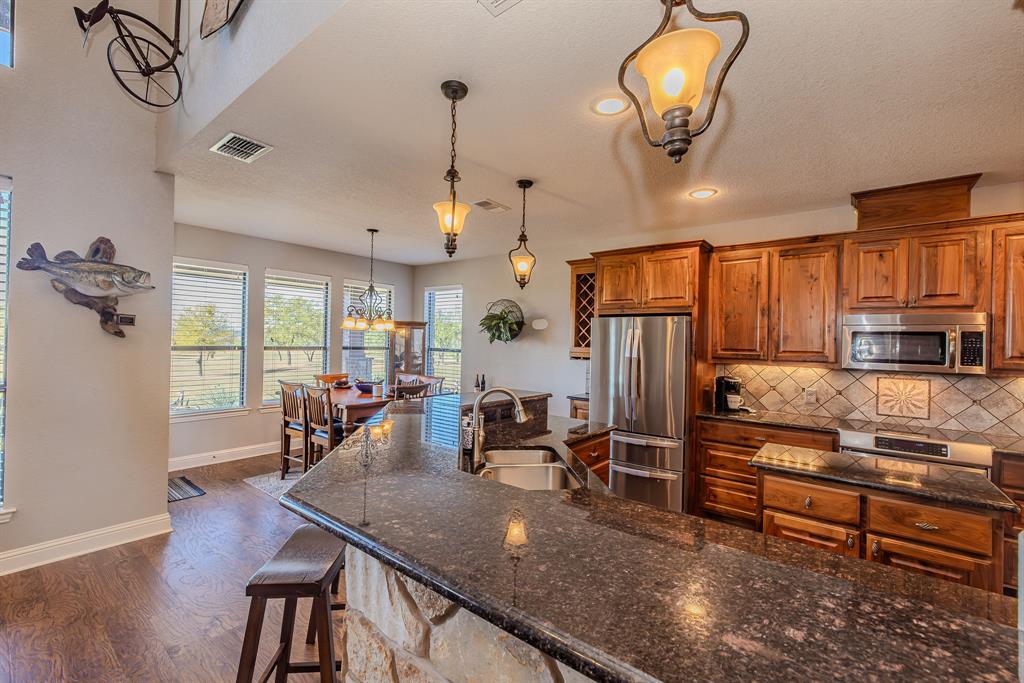 401 Frog Branch Court Graford, TX 76449 - Photo 11 of 40 a kitchen with stainless steel appliances granite countertop a sink dishwasher a stove and a refrigerator with wooden floor