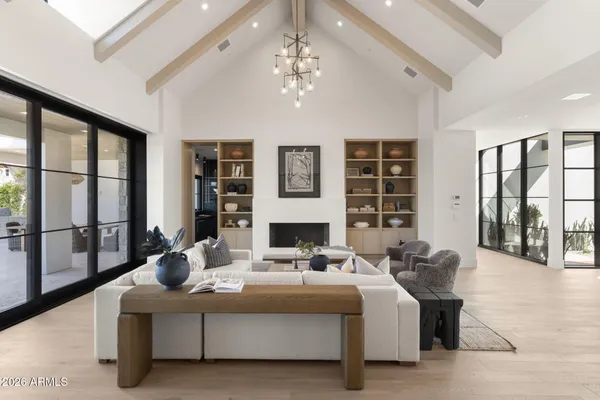 a living room with furniture large windows and wooden floor