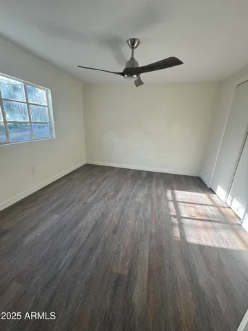 a view of empty room with wooden floor and fan