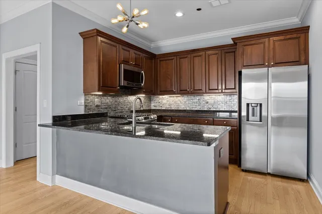 a kitchen with stainless steel appliances granite countertop a refrigerator a sink a stove a microwave and island