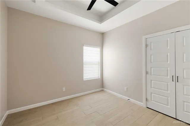 an empty room with windows and ceiling fan