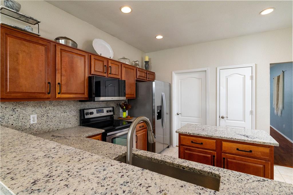 4025 Chisos Rim Trail Fort Worth, TX 76244 - Photo 12 of 40 Kitchen featuring granite countertops, wood cabinetry, stainless steel appliances, and recessed lighting