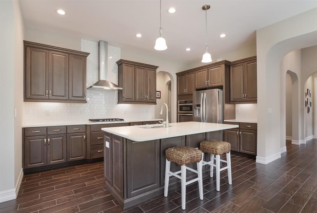 2402 Starwood Court Lakewood Ranch, FL 34211 - Photo 14 of 71 a kitchen with stainless steel appliances granite countertop a table chairs sink refrigerator and cabinets