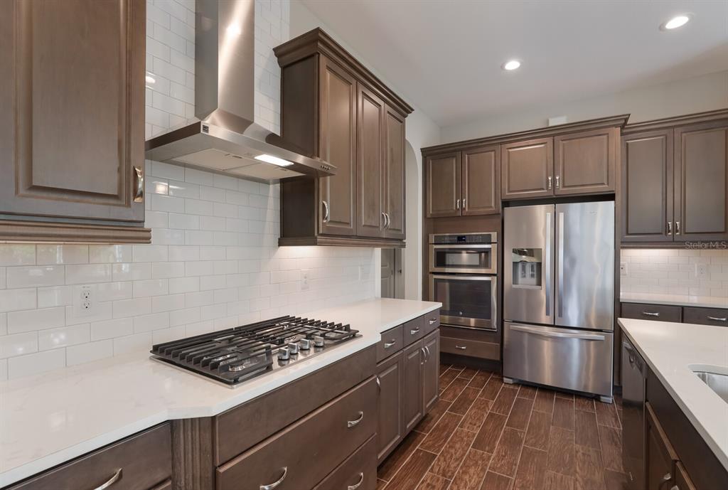 2402 Starwood Court Lakewood Ranch, FL 34211 - Photo 18 of 71 a kitchen with kitchen island stainless steel appliances a stove a sink and a refrigerator