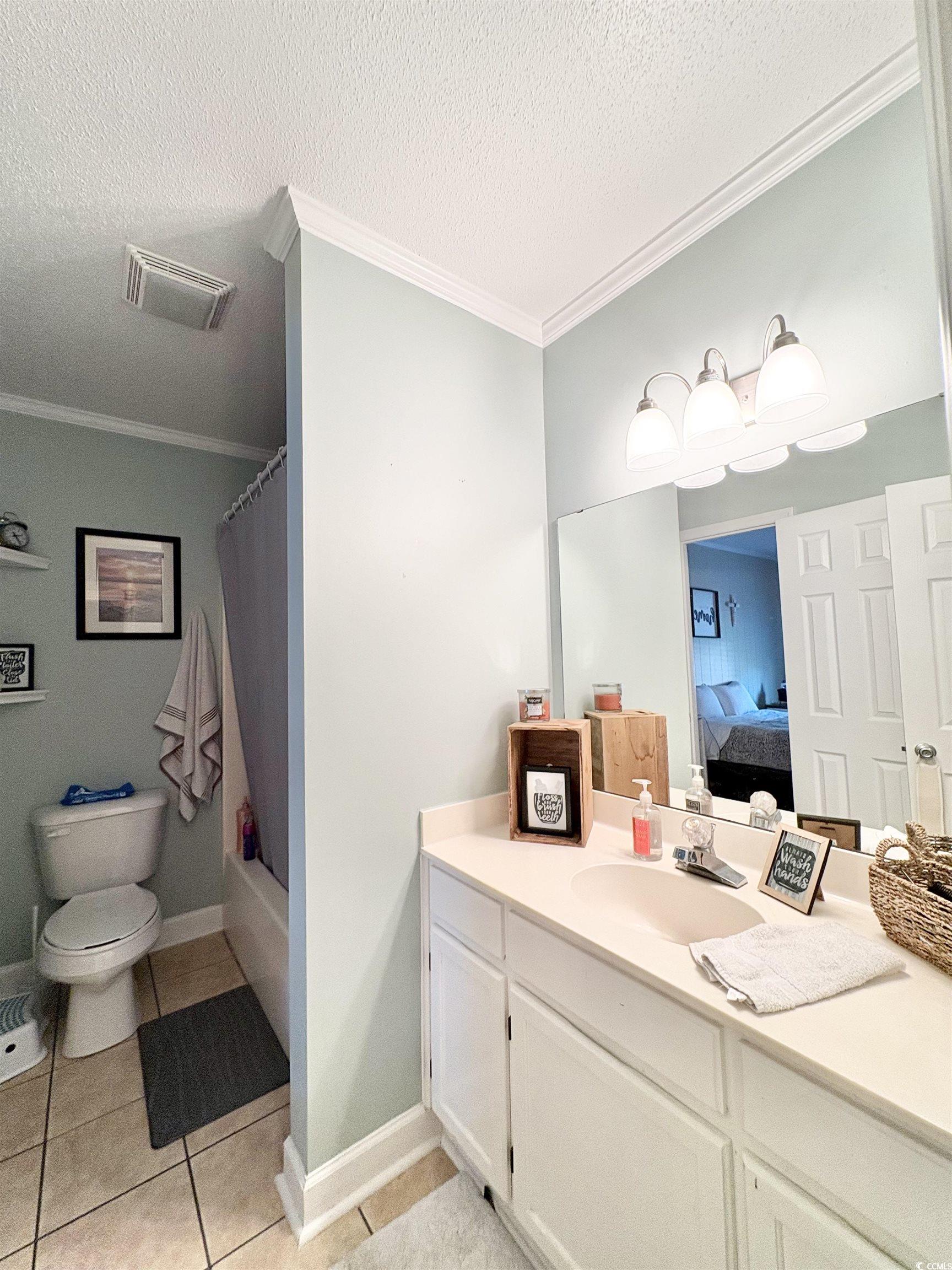 520-526 Boundary Avenue Murrells Inlet, SC 29576 - Photo 11 of 38 Full bathroom featuring ornamental molding, vanity, shower / bathtub combination with curtain, a textured ceiling, and light tile patterned floors