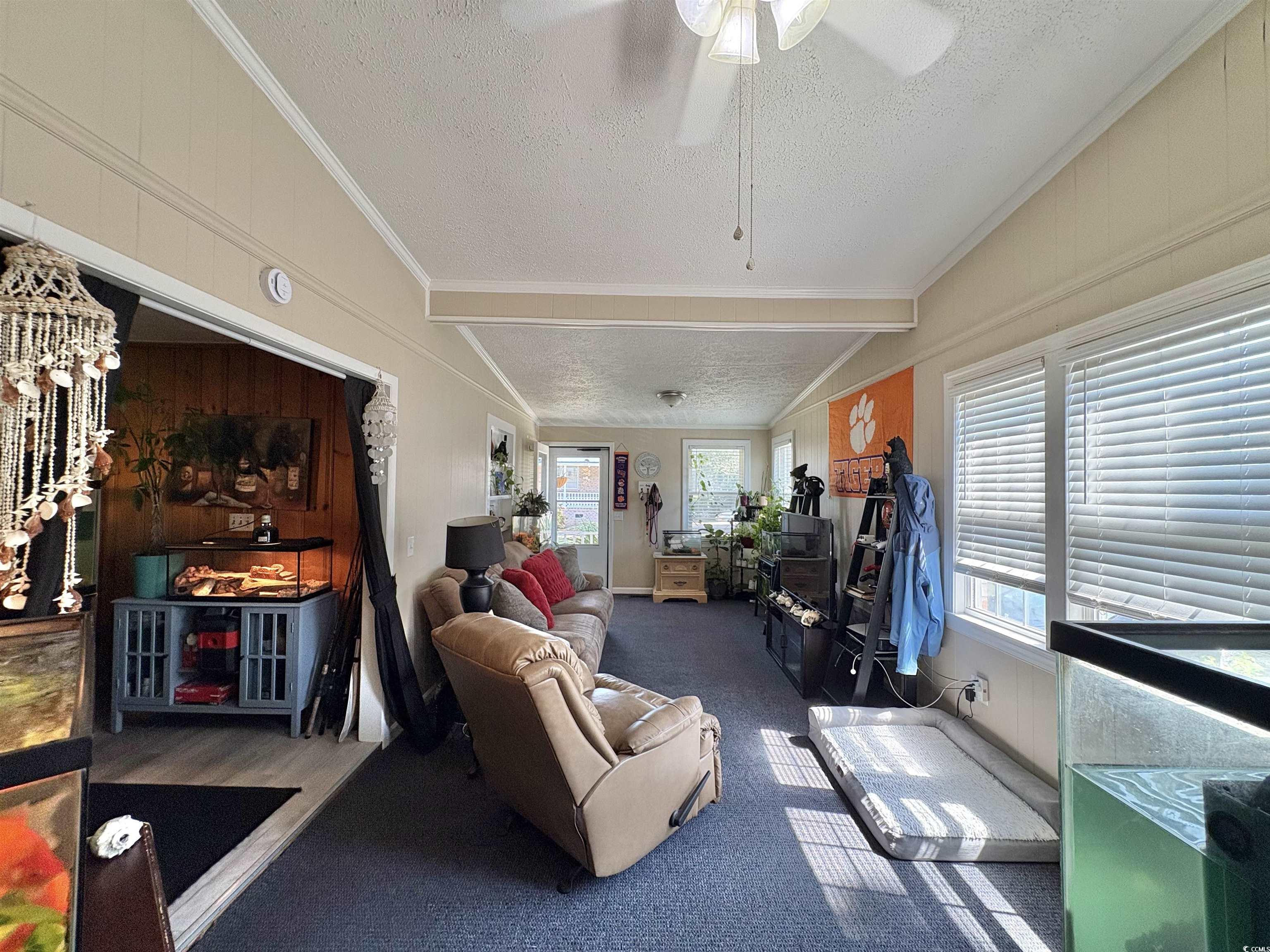 520-526 Boundary Avenue Murrells Inlet, SC 29576 - Photo 22 of 38 Carpeted living room with a textured ceiling, wooden walls, ornamental molding, and ceiling fan