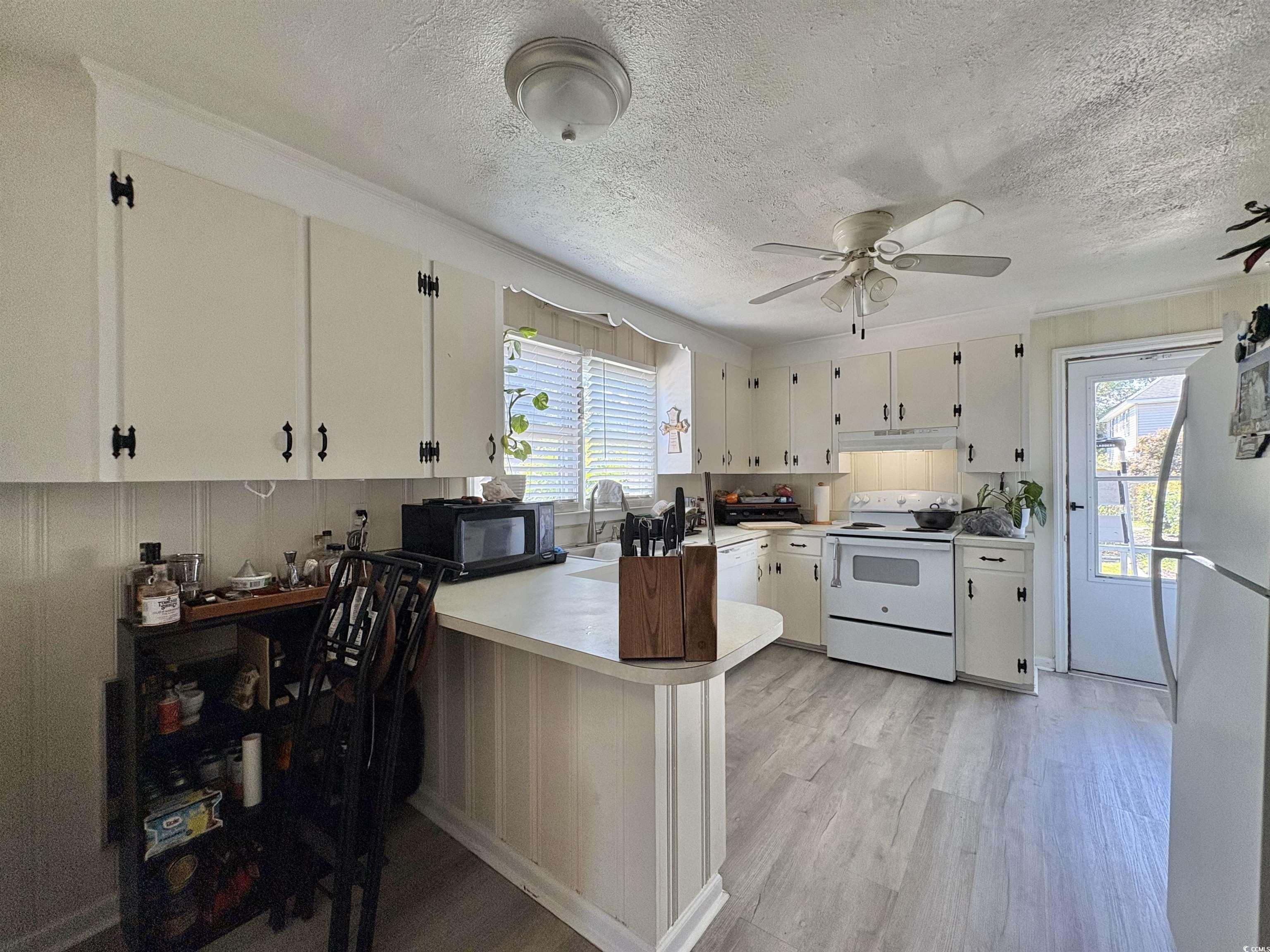 520-526 Boundary Avenue Murrells Inlet, SC 29576 - Photo 24 of 38 Kitchen featuring white appliances, a peninsula, light countertops, light wood-style floors, and a textured ceiling