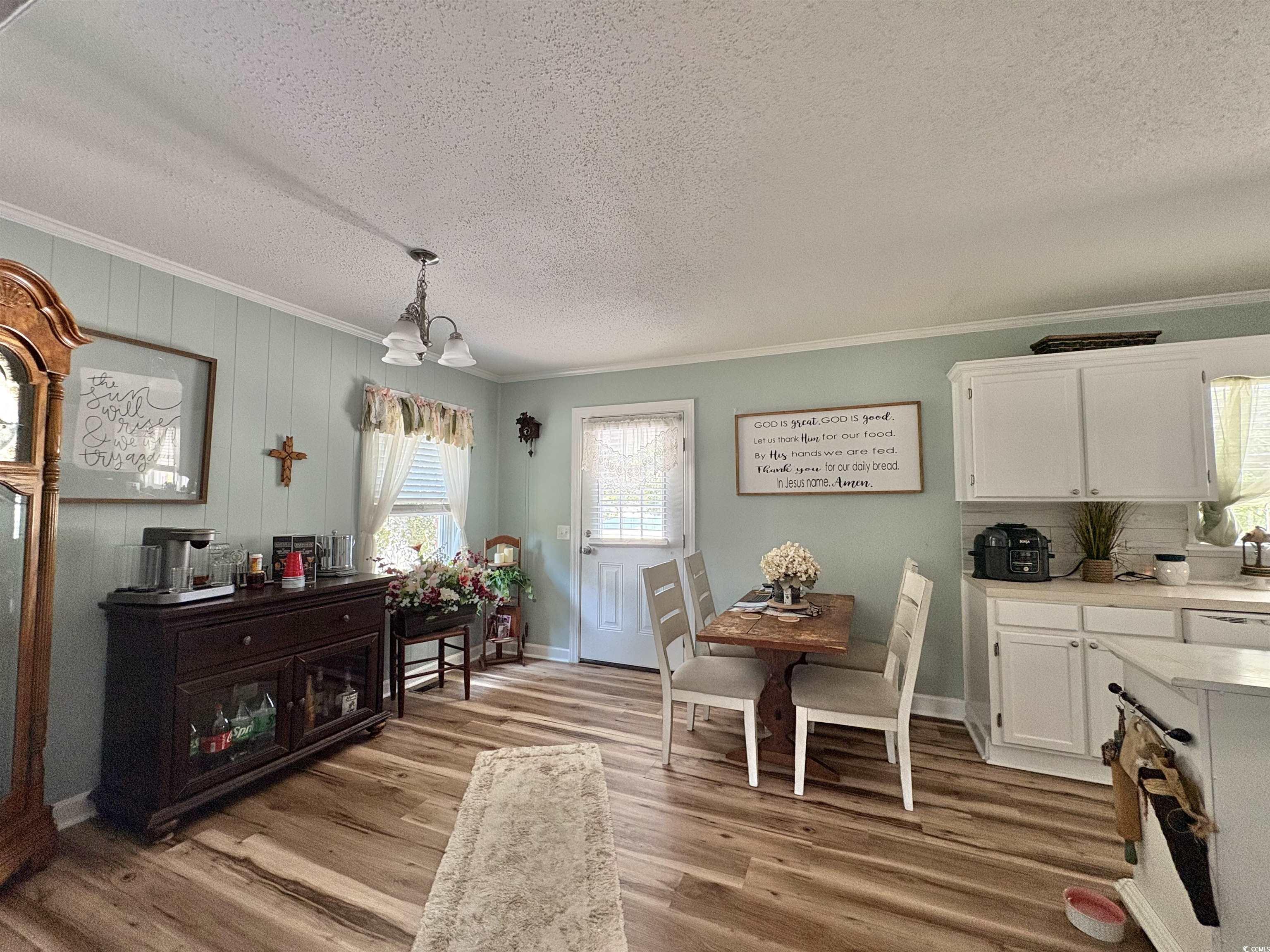 520-526 Boundary Avenue Murrells Inlet, SC 29576 - Photo 6 of 38 Dining space featuring crown molding, light wood-type flooring, plenty of natural light, a textured ceiling, and a chandelier