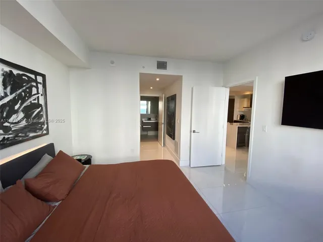 a room with a bed and large windows