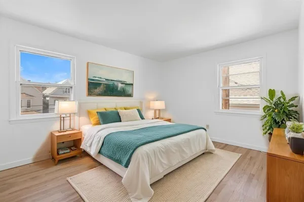 a bedroom with a large bed a potted plant and a window