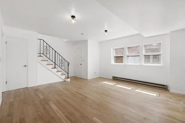a view of an empty room with wooden floor and stairs