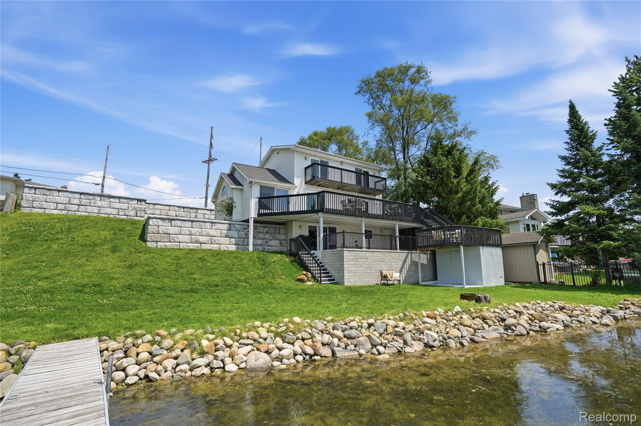 7217 Andersonville Road Clarkston, MI 48346 - Photo 49 of 65 Waterfront property featuring a tiered retaining wall, multiple balconies, a lower patio, and a private dock