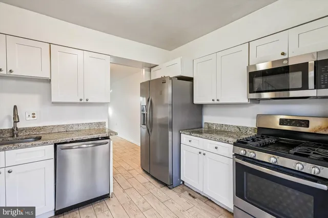 a kitchen with stainless steel appliances white cabinets and a stove top oven