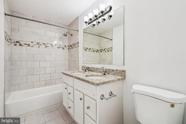a bathroom with a granite countertop sink a toilet and shower