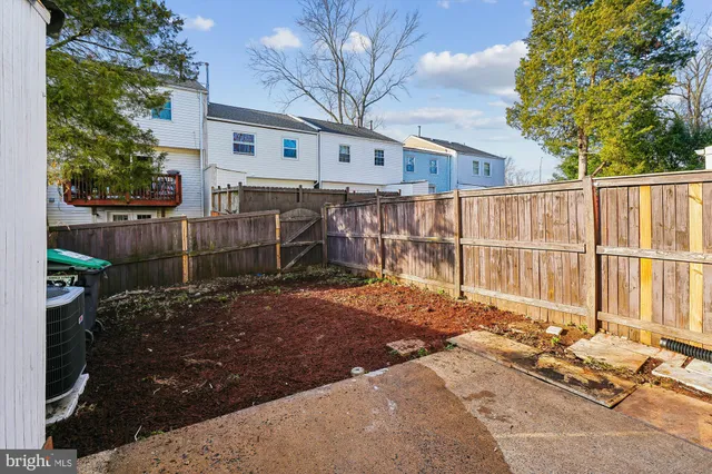 a backyard of a house with wooden fence and large trees
