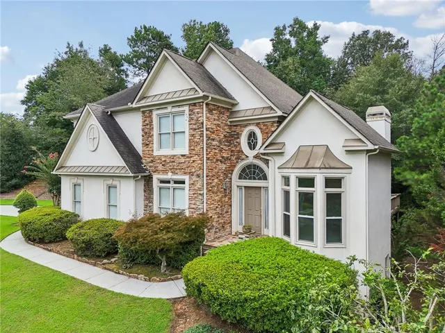 a view of a white house next to a yard with large trees