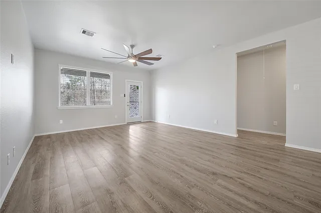 an empty room with windows and fan