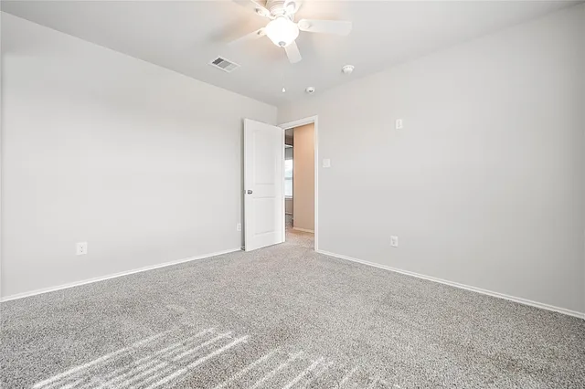 an empty room with a chandelier fan and closet area